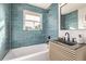 Updated bathroom with teal tile, floating vanity, and a bathtub at 5550 E Thrill Pl, Denver, CO 80207