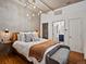 Cozy bedroom with concrete ceiling, wood floors, modern light fixture, and ensuite bathroom at 1499 Blake St # 3U, Denver, CO 80202