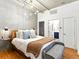 Cozy main bedroom featuring a comfortable bed, modern lighting, hardwood floors, and a view into an ensuite bathroom at 1499 Blake St # 3U, Denver, CO 80202