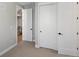 Hallway featuring white doors with black hardware, with a view to the staircase and upstairs area at 5004 S Platte River Pkwy, Littleton, CO 80123