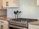 Close up on cook top and subway tile backsplash in modern kitchen with gray counter tops at 5004 S Platte River Pkwy, Littleton, CO 80123