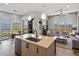 Bright, open kitchen featuring an island with sink, pendant lighting, and stainless steel appliances, seamlessly flowing into the living area at 5004 S Platte River Pkwy, Littleton, CO 80123