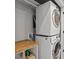 Efficient laundry room with stacked washer and dryer and a wooden folding counter at 5004 S Platte River Pkwy, Littleton, CO 80123