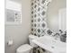 Stylish powder room with a pedestal sink, patterned tile accent wall, and a round mirror at 5004 S Platte River Pkwy, Littleton, CO 80123
