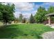 Spacious backyard featuring a lush lawn, mature trees, and a charming playset for children at 7119 S Riviera St, Aurora, CO 80016