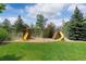 Spacious backyard featuring a lush lawn, mature trees, and a charming playset for children at 7119 S Riviera St, Aurora, CO 80016