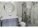 Compact bathroom with a modern vanity, round mirror, toilet, and glass enclosed marble tiled shower at 7119 S Riviera St, Aurora, CO 80016