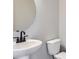 Modern powder room with pedestal sink, toilet, and round mirror at 9656 Browns Peak Cir, Littleton, CO 80125