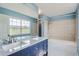 Bright bathroom featuring a double sink vanity, marble countertop, and a bathtub with shower at 13504 E Asbury Dr, Aurora, CO 80014