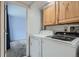 Practical laundry area with modern washer and dryer, and wood cabinets at 13504 E Asbury Dr, Aurora, CO 80014