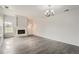 Open living room featuring a cozy fireplace, light gray wood floors, and a chandelier at 13504 E Asbury Dr, Aurora, CO 80014