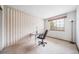 Bright office space with wood-paneled walls, large window, carpet flooring, and a modern black desk at 20738 E Grand Pl, Aurora, CO 80015