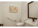 Simple half-bathroom with a sink and toilet beneath neutral artwork with bronze fixtures at 5530 Racquet Ln, Boulder, CO 80303