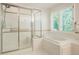 Bright bathroom with a glass shower and bathtub with shuttered windows at 5530 Racquet Ln, Boulder, CO 80303