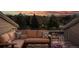 Comfortable seating on a rooftop deck with flowers and views of mature trees and mountains at dusk at 7066 W 13Th Ave, Lakewood, CO 80214