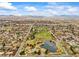 Expansive aerial view of neighborhood with park featuring a pond, green spaces, and mountain backdrop at 7100 W Ellsworth Pl, Lakewood, CO 80226