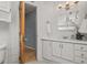 Bright bathroom features white cabinets, countertop, large vanity mirror, and wood door entrance at 7100 W Ellsworth Pl, Lakewood, CO 80226