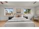 Sun-filled bedroom featuring hardwood floors, two windows, and a ceiling fan at 7100 W Ellsworth Pl, Lakewood, CO 80226