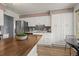 Well-lit kitchen featuring white cabinetry, a butcher block island, stainless steel appliances, and dark backsplash at 7100 W Ellsworth Pl, Lakewood, CO 80226