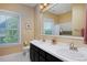 Bright bathroom featuring double vanity sinks, walk-in shower, and a window at 8171 E 33Rd Ave, Denver, CO 80238
