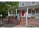 Inviting front porch featuring a vibrant red door, white pillars, lush landscaping, and brick accents, creating a warm entrance at 8171 E 33Rd Ave, Denver, CO 80238