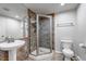 Well-lit bathroom featuring a tiled shower with glass enclosure, pedestal sink, and white toilet at 10609 Abilene St, Commerce City, CO 80022