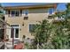 Back exterior featuring light yellow siding, a sliding door, and mature foliage at 10609 Abilene St, Commerce City, CO 80022