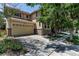 Two-story home with a two car garage, brick accents, mature trees, and a concrete driveway at 10609 Abilene St, Commerce City, CO 80022