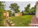 View of the backyard with two sheds, lush green lawn, mature trees and a small windmill at 6072 Pierson Ct, Arvada, CO 80004