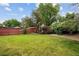 Sprawling green lawn, mature leafy trees, and a decorative fence surround the property in the spacious back yard at 3298 S Krameria St, Denver, CO 80222