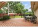 A cozy back porch features wood floors, wrought iron chairs, green lawn, a wood fence and leafy trees at 3298 S Krameria St, Denver, CO 80222