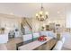 Open-concept dining area with a long dark wood table, statement chandelier, and adjoining kitchen at 15723 E Orchard Pl, Aurora, CO 80016