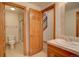 Bright bathroom features a tile floor, shower and toilet in a room with natural wood trim and a tile sink at 5951 Rain Dance Trl, Littleton, CO 80125