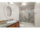 Bathroom featuring marble tile shower with glass doors, granite countertop, and oval mirror at 7761 S Curtice Dr # C, Littleton, CO 80120