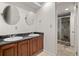 Bathroom featuring double sinks, granite countertop, mirrors and a shower in an alcove at 7761 S Curtice Dr # C, Littleton, CO 80120