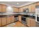 Well-lit kitchen boasting stainless steel appliances, granite counters, wood cabinets and hardwood floors at 7761 S Curtice Dr # C, Littleton, CO 80120