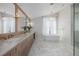 Bright main bathroom featuring double sinks, marble floors, soaking tub, and a window at 2365 S Clayton St, Denver, CO 80210