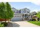 Attractive two-story home featuring blue siding, a two-car garage, a well-maintained lawn, and lush landscaping at 10057 Des Moines St, Parker, CO 80134
