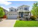 Inviting two-story home with a blue front door, attractive siding, a two-car garage, and a beautifully landscaped front yard at 10057 Des Moines St, Parker, CO 80134