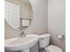 Half bath featuring pedestal sink, toilet, and round mirror at 9351 Amison Cir # 104, Parker, CO 80134