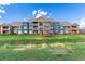 Low angle exterior of blue and tan apartment building with brick accents and multiple balconies against a bright blue sky at 804 Summer Hawk Dr # 303, Longmont, CO 80504