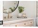 Modern bathroom features a pink vanity, gold hardware, round mirror and decor at 7050 W Cedar Ave # 108, Lakewood, CO 80226