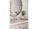 Modern bathroom features a pink vanity, gold hardware, round mirror, and gold faucet at 7050 W Cedar Ave # 108, Lakewood, CO 80226