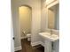 Elegant powder room features a pedestal sink, arched doorway to water closet, and wood floors at 6023 Chester Way, Denver, CO 80238
