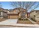 Two-story beige home with brown trim, stone accents, a two-car garage and a concrete driveway, surrounded by green bushes and a bare tree at 10677 Cedarcrest Cir, Highlands Ranch, CO 80130