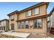 Back exterior of a tan two-story house with large windows and a small patio at 10677 Cedarcrest Cir, Highlands Ranch, CO 80130