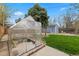 Backyard featuring a greenhouse, storage shed, green lawn, and a concrete patio at 835 S Shoshone St, Denver, CO 80223