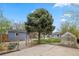 Spacious backyard featuring a concrete patio, large tree, storage shed and greenhouse at 835 S Shoshone St, Denver, CO 80223