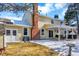Back of home featuring a patio, brick chimney, sliding glass doors, manicured lawn, and snow at 7631 Oak St, Arvada, CO 80005
