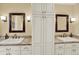 Bathroom featuring dual sinks, granite countertops, a central cabinet, and sconce lighting at 7631 Oak St, Arvada, CO 80005